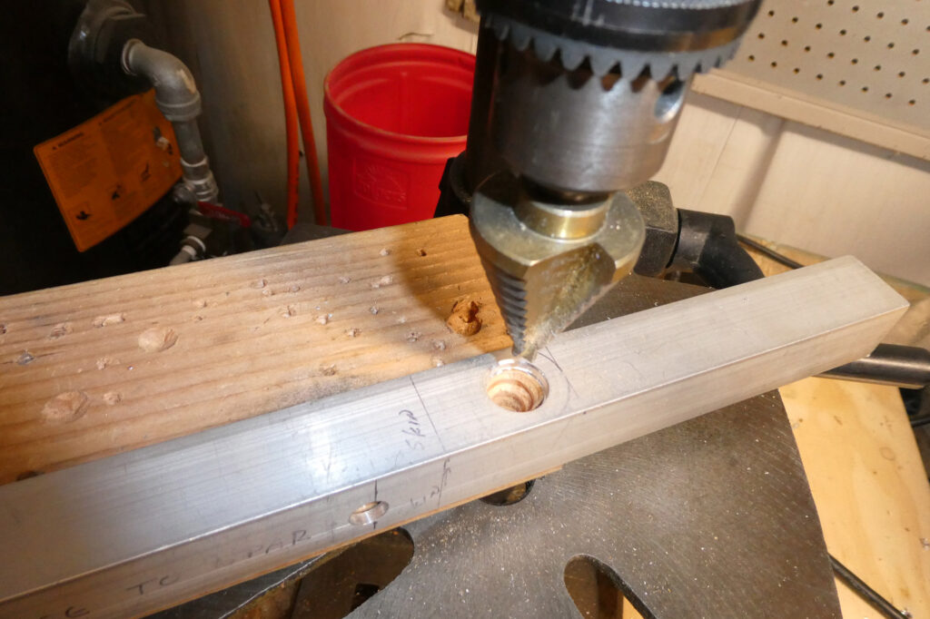 Using a uni-bit to drill out the tie-down hole.