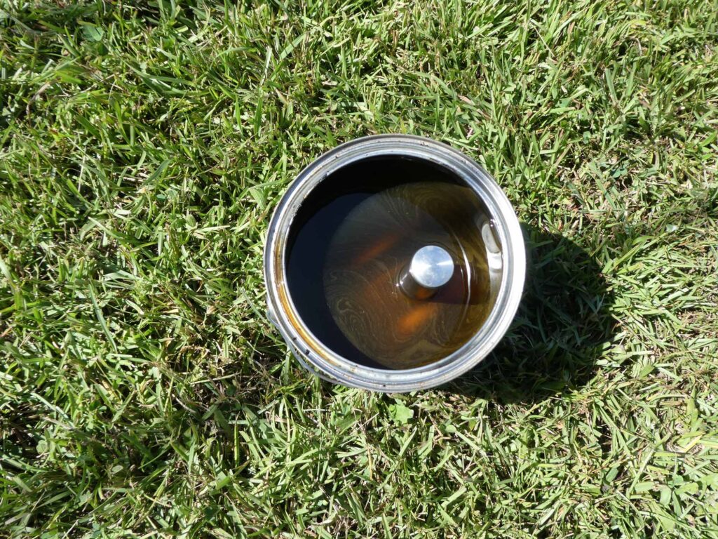 A piston enjoying a 20-30 minute soak in the carb cleaner. Leaving the wrist pin partially installed made for a convenient handle.