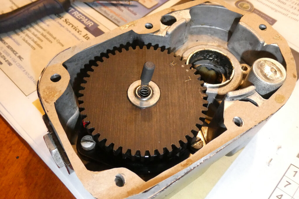 The culprit brush, in its stuck position, flanked by the replacement rotor and another new carbon brush and spring (sitting on the small cup).