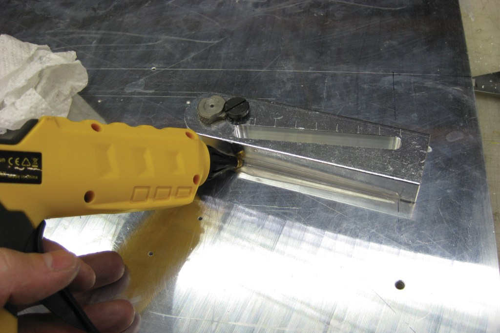Using a glue gun to affix a drill guide where a clamp doesn’t reach.