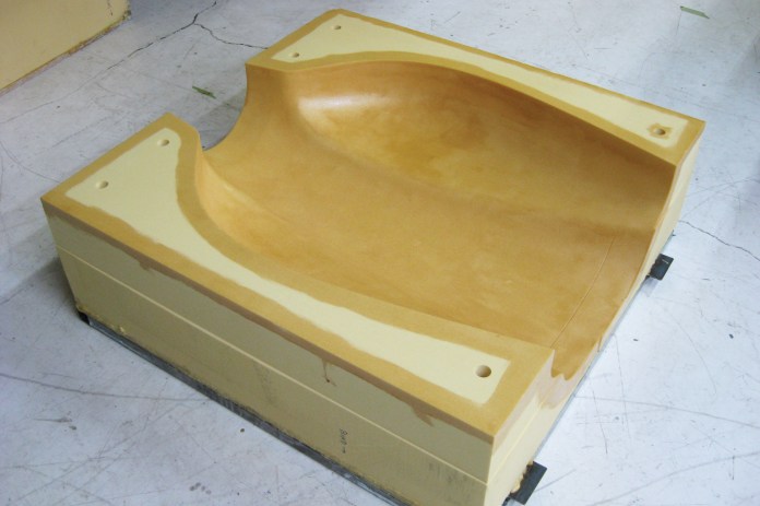 Top cowl showing holes for alignment pins, and epoxy coat. Thinned epoxy is brushed on the mold surface, as well as corners/edges of the mold. This is for durability, as the mold foam is quite light (6lbs per cubic foot); the resin soaks in and toughens the surface of the mold.