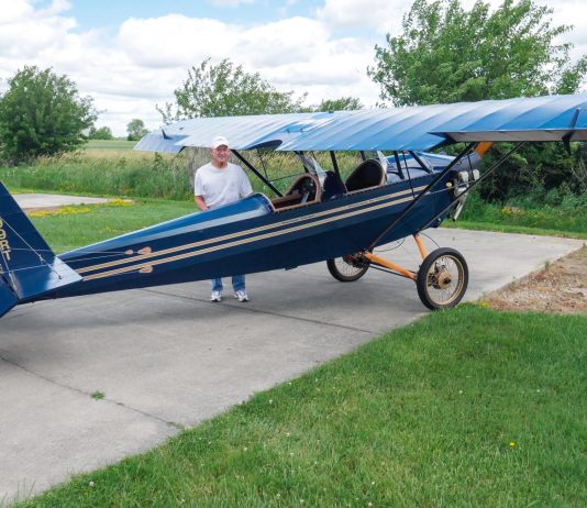 R.T. Searfoss shows off his magnificent workmanship in the Pietenpol Air Camper he built over the span of 12 years. There is much to love in classic tube and fabric aircraft which harken back to an earlier time of aircraft construction. Masterful craftsmanship is everywhere you look in R.T.’s work. [Credit: Bill Wilson]