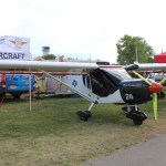 Black and white Zenith CH 750 Cruzer parked in front of Zenith Aircraft tents at Oshkosh